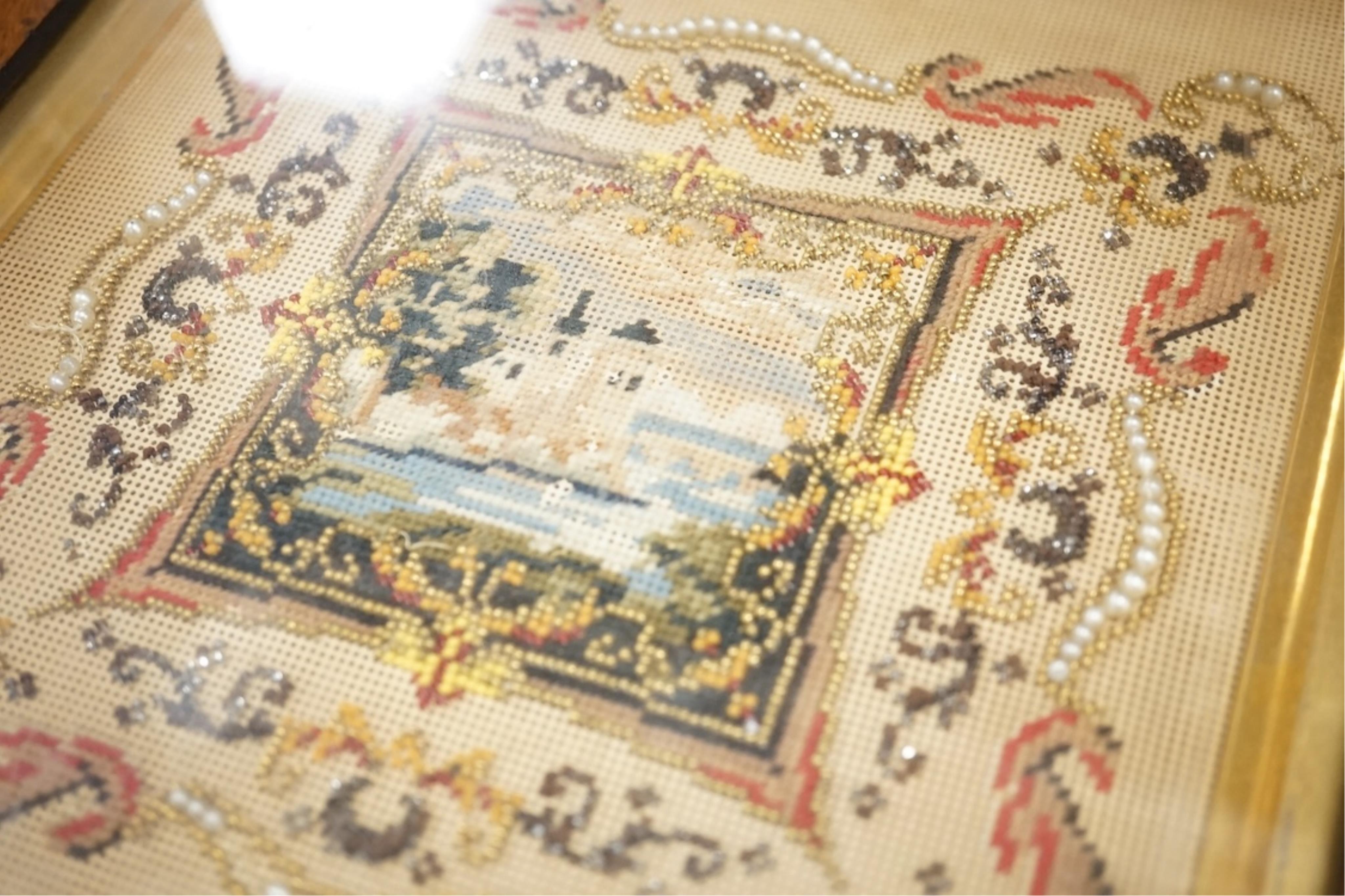 A framed 19th century Berlin bead worked embroidery, worked as a small cartouche of a moated castle with a decorative border, overall 30cm high